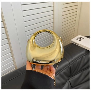 Detail of golden moon-shaped metal clutch with mirror finish and bead chain strap
