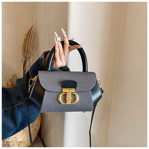 Detailed view of grey canvas and black leather handbag with golden CD metal buckle
