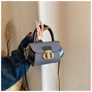 Detailed view of the luxury dual-tone grey denim and black leather handbag with gold T-lock