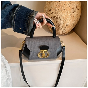 Macro view of tweed texture and golden metal clasp on black and gray crossbody bag
