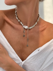 Detail of baroque pearl necklace with metallic beads and star pendants on a model