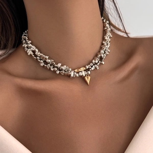 Detail of irregular silver beads choker with a golden heart pendant on model