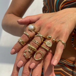Set di anelli d'oro con texture geometriche irregolari e accento di perla singola