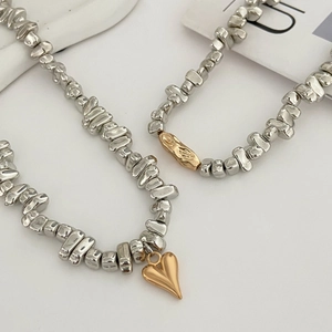 Detail view of crushed silver-tone metal beads with gold heart and bar pendants