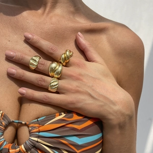 Set di quattro anelli geometrici in oro spesso con finiture lisce e materiche su modella