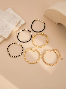 Détail d'un ensemble de six bracelets dorés et noirs avec perles et pendentif pièce