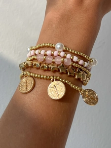 Détail de bracelets bohèmes multicouches dorés avec perles roses et pendentifs pièces