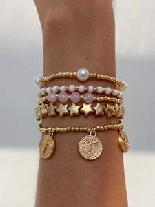Gros plan de bracelets de perles empilés avec pierres roses et pendentif doré