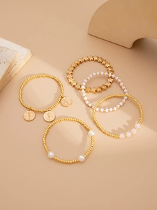 Détail d'un lot de cinq bracelets dorés vintage avec perles et breloques