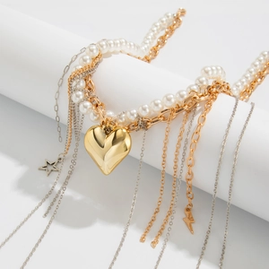 Détail de pendentifs cœur et étoile dorés sur chaînes mixtes de perles et métal