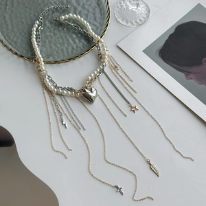 Détail du collier à pampilles argentées avec pendentif cœur, étoiles et croix