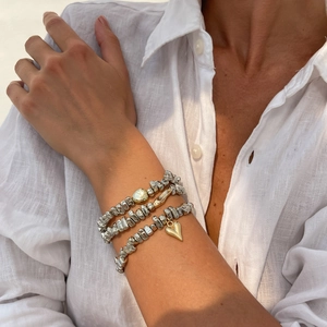 Ensemble de bracelets à billes argentées avec breloque cœur doré sur fond de lin blanc