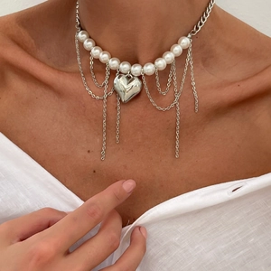 Détail du collier à pendentif cœur argenté avec perles et chaînes à glands sur le cou