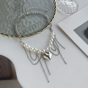 Détail du collier à pendentif cœur argenté avec chaîne en perles et glands métalliques
