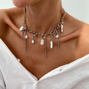 Gros plan d'un collier chaîne argenté avec perles baroques et pampilles sur un mannequin