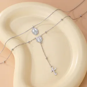 Détail du collier argenté multicouche avec médailles Vierge Marie et pendentif croix