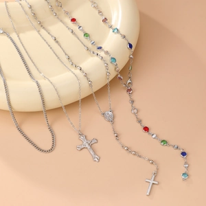 Gros plan de colliers avec croix religieuses argentées et perles colorées sur plat céramique