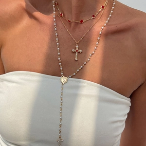 Gros plan détaillé d'un collier doré à trois rangs avec pendentif croix et perles