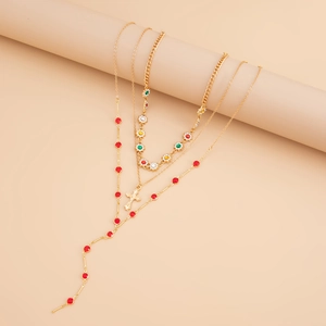 Détail d'un ensemble de trois colliers dorés avec fleurs en cristal et pendentif croix