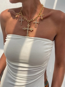 Makroaufnahme einer goldenen Schichtkette mit fünf kreuzförmigen Strass-Anhängern am Model