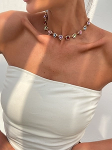 Détail du collier cœur en cristal coloré avec pierres arc-en-ciel sur une chaîne dorée