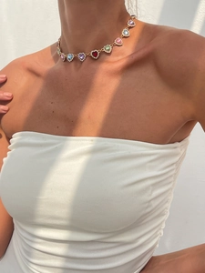 Détail d'un collier ras du cou doré avec cristaux colorés en forme de cœur et diamants
