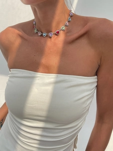 Gros plan d'un collier de cristaux colorés en forme de cœur sur un mannequin au soleil