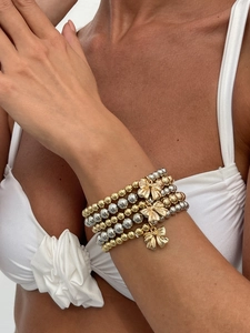 Detail of multi-layer beaded bracelets with golden bow charms on model wrist