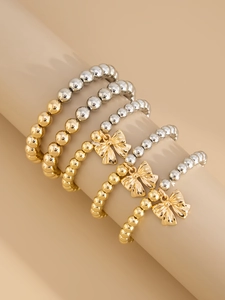 Detailed view of five-piece stacked CCB beaded bracelets with gold bow charms