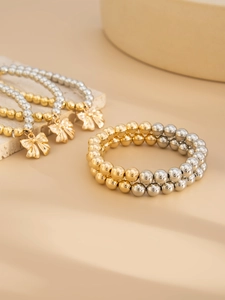 Detail of beaded bracelet set with gold bow charms on minimalist stone display