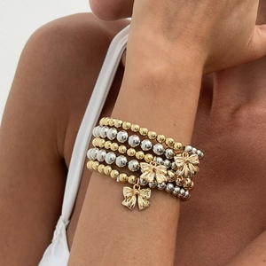 Five-layer stacked bead bracelet with gold and silver spheres and bow charms