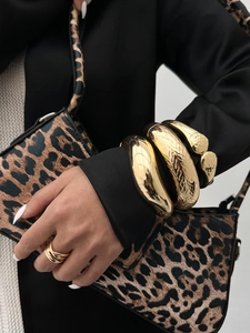 Macro detail of chunky gold bangles with smooth, embossed, and hammered textures