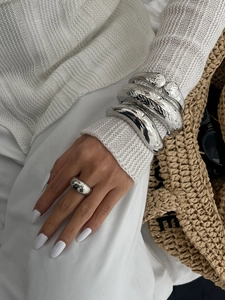 Detail shot of chunky silver metal bracelets and rings paired with elegant fashion accessories