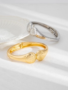 Close-up of minimalist gold and silver spring bracelets with hammered round texture detail
