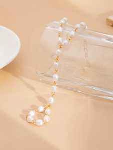 Detailansicht eleganter unregelmäßiger Perlen und goldener Metallglieder auf Glas