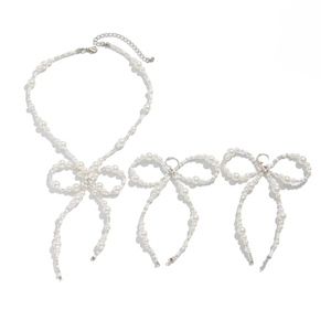 Elegant pearl jewelry set with bow tie necklace and earrings on a white background