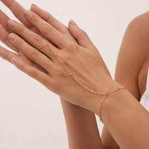 Détail d'un bracelet bague doré avec perles délicates et anneau minimaliste sur la main