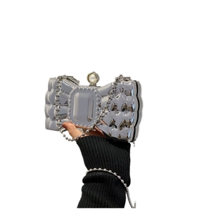Silver bow-shaped evening clutch bag with quilted texture, pearl clasp and metal chain