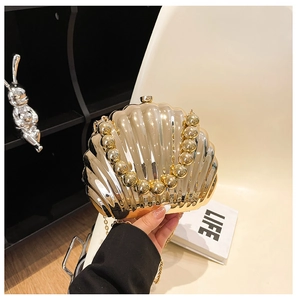 Detail of shell-shaped evening bag with gold metallic finish and large bead handle