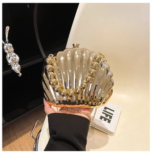 Detail of golden shell evening clutch bag with pearl handle and metal chain strap