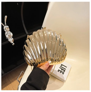 Detail of a metallic gold shell shaped clutch with acrylic chain and mirror finish