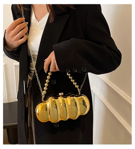Close-up of golden wavy cloud-shaped acrylic evening bag with beaded handle and chain strap