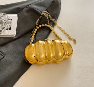 Close-up of metallic gold acrylic evening bag with wavy texture and beaded handle