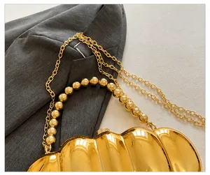 Detail of golden wavy acrylic evening bag with bead handle and metal chain strap