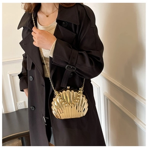 Close-up of golden shell-shaped metallic crossbody bag with chain strap and top handle