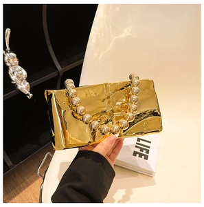 Detail view of a luxury gold mirror mini bag with beaded handle and high-shine finish