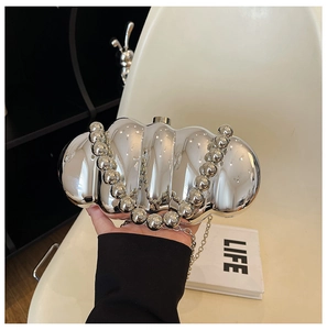 Detailed view of silver metallic shell bag with wave texture and beaded handle