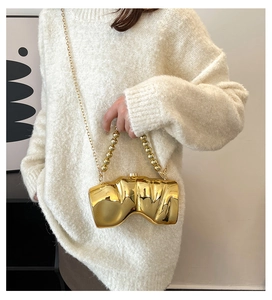 Detailansicht einer unregelmäßigen goldfarbenen Abendtasche mit Perlensteg und Metallkette