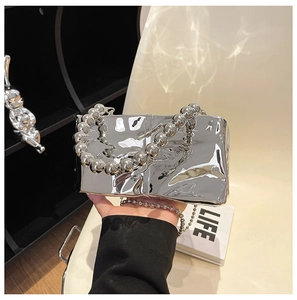 Detail view of silver mirror finish rectangular handbag with large bead handle decoration
