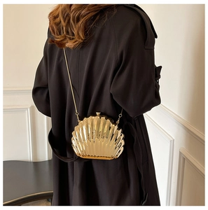 Detailed view of a gold shell-shaped clutch with metallic ripples and chain strap